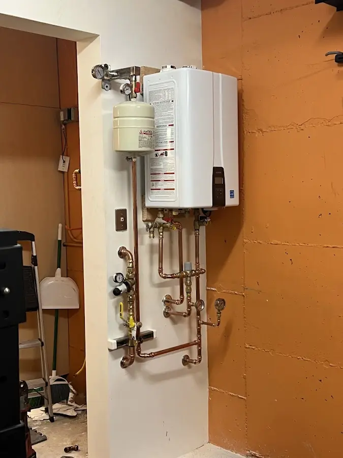 Plumbing technician inspecting water heater connections in Westover